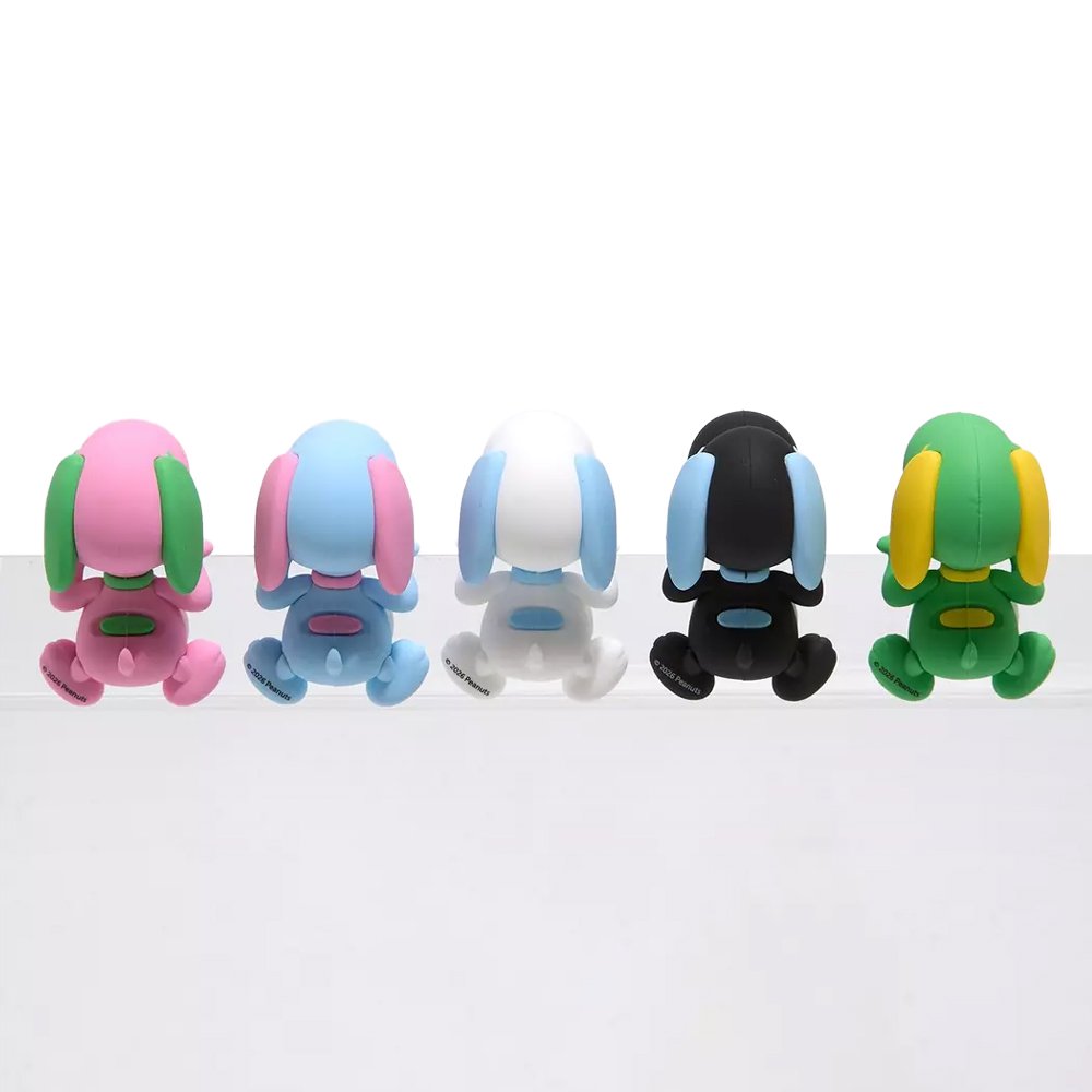 Five colorful miniature Snoopy figures in pastel sherbet colors designed to hang from edges, shown alongside a close-up of a blue and pink Snoopy figure clinging to the corner of a smartphone.
