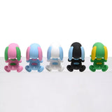 Five colorful miniature Snoopy figures in pastel sherbet colors designed to hang from edges, shown alongside a close-up of a blue and pink Snoopy figure clinging to the corner of a smartphone.
