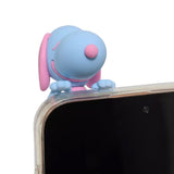 Five colorful miniature Snoopy figures in pastel sherbet colors designed to hang from edges, shown alongside a close-up of a blue and pink Snoopy figure clinging to the corner of a smartphone.
