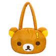 An officially licensed Rilakkuma puffy face crossbody bag in a brown color. It has a white muzzle with a brown nose and mouth, large dark eyes, and long padded shoulder straps. A small yellow exclamation point charm hangs from the base of one handle.