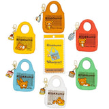 A collection of officially licensed Rilakkuma mystery keychains in a variety of colors. Each keychain is shaped like a small tote bag featuring Rilakkuma and a "have a nice day!" message, and each includes a unique food-themed charm like pancakes or pudding.