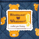 An officially licensed Rilakkuma reversible quilted backpack in navy denim blue. The front features a repeating pattern of Rilakkuma's face and a zippered front pocket.