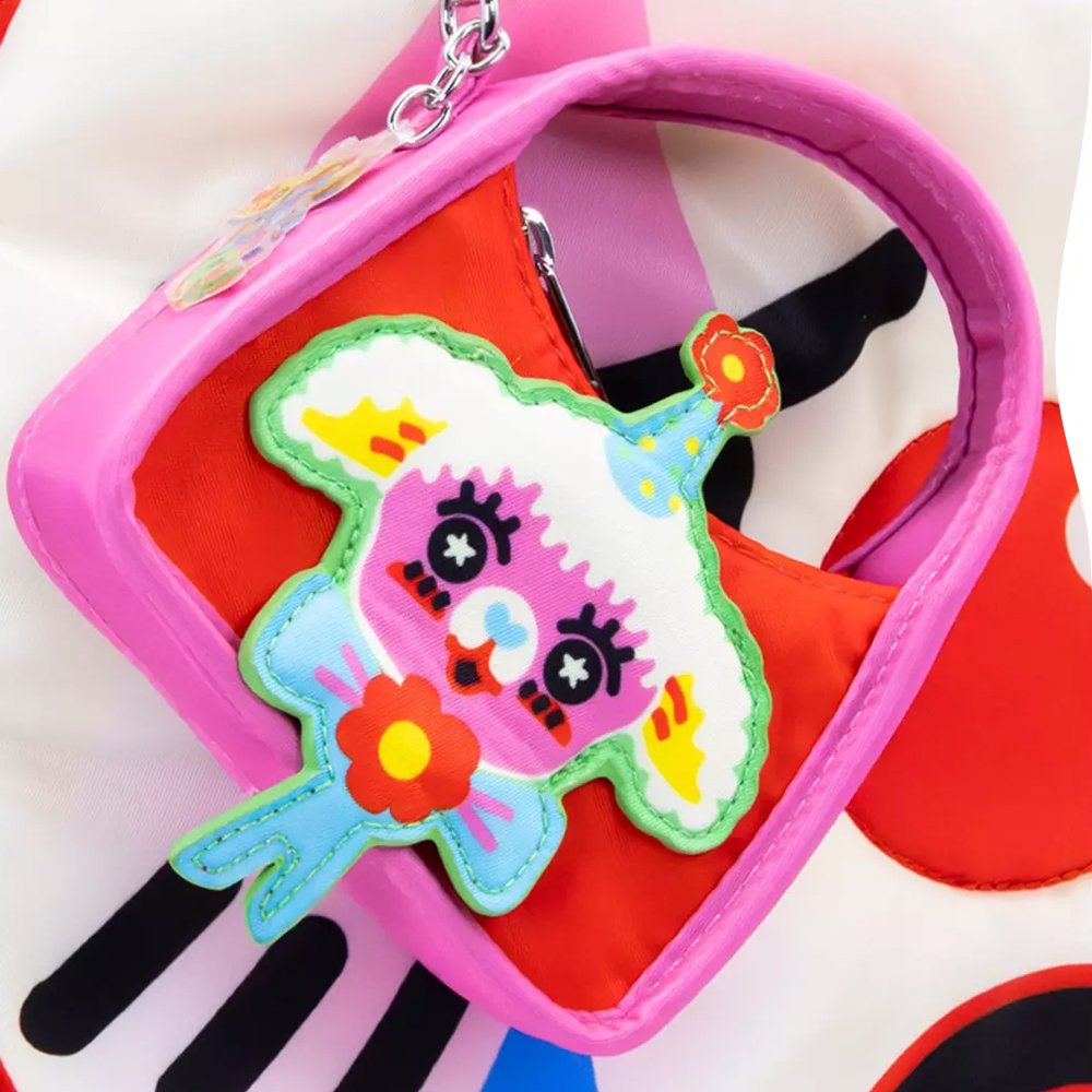 Six miniature, colorful baguette-shaped bag charms featuring whimsical circus animal faces designed by artist So Lazo, arranged around a green and yellow mystery packaging box

