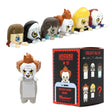 Six Warner Bros horror mystery blind box phone buddy mini figures lined up featuring Annabelle, The Nun, Regan, Pennywise, David, one secret Chase style