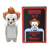 Six Warner Bros horror mystery blind box phone buddy mini figures lined up featuring Annabelle, The Nun, Regan, Pennywise, David, one secret Chase style