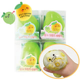Four individual clear boxes of green-to-yellow color-changing Crunchy Mango Squishy Toys with Korean text, alongside a close-up inset of a hand squeezing the soft squishy showing internal yellow ASMR crunch beads, perfect for stress relief, anxiety relief, party favor goodie bag fillers, Christmas stocking stuffers, and holiday gift sets