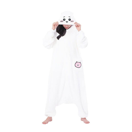 Official SAZAC Chiikawa Kigurumi Vol. 2 Costume Onesie Jumpsuit worn by a model. Features a soft white fleece body, Chiikawa face hood with blush details, and the upgraded pink bear pochette pocket embroidery. Perfect for Halloween costumes, cozy sleepover nights, and cosplay party loungewear for anime fans