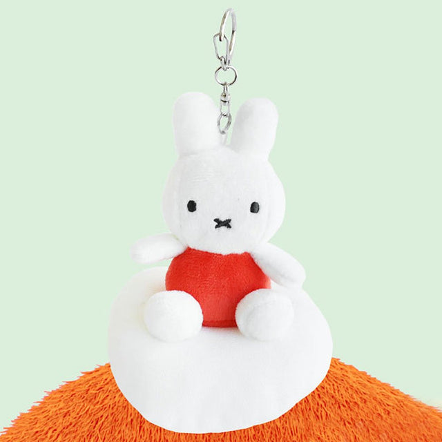 Plush keychain of Miffy character in an orange outfit sitting on the cloud