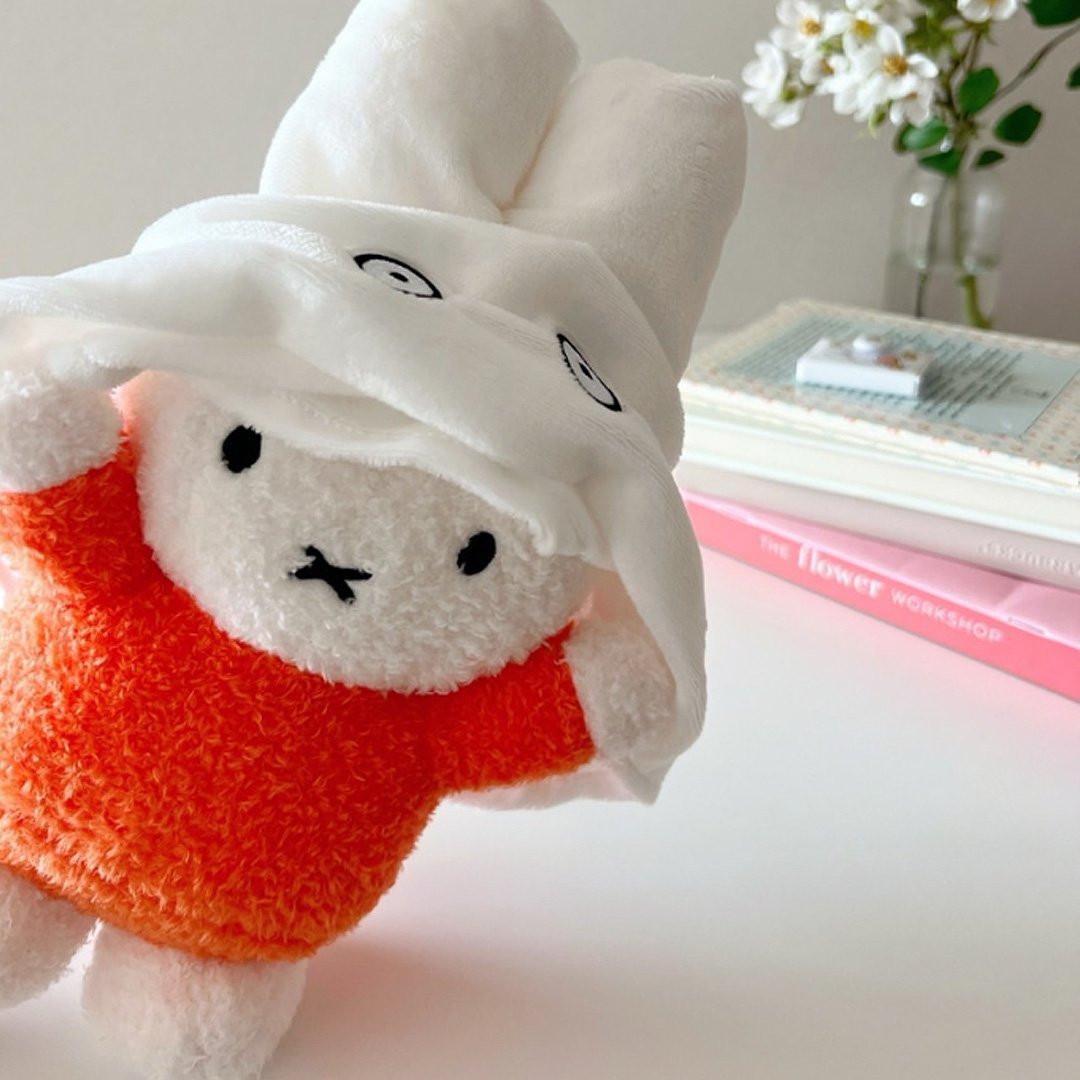 Official Miffy Ghost Plush with removable white ghost cover and signature orange shirt. Soft aesthetic Miffy rabbit stuffed animal for Halloween and Valentine's Day gift, styled on a white desk with floral decor.