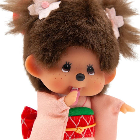 Close-up view of Sekiguchi Monchhichi Sakura Kimono Girl Clip-On Mascot Plush Keychain showing adorable face, pacifier accessory, twin pigtails with cherry blossom hair pins, and pink kimono detail, ideal holiday stocking stuffer