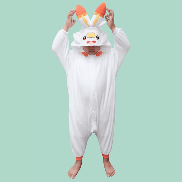 Front view of Officially Licensed Pokémon Scorbunny Kids Fleece Kigurumi Onesie Jumpsuit featuring white cozy winter pajamas with orange rabbit ears hood, yellow nose patch, and orange cuffs, perfect Halloween costume, Christmas gift, warm kids sleepwear, and anime cosplay outfit