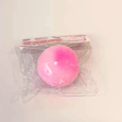 Hands squeezing a soft pink Strawberry Rice Cake Bread Squishy Toy through its clear plastic packaging, demonstrating squishy elasticity and doughy feel for fidget lovers and holiday gift guides