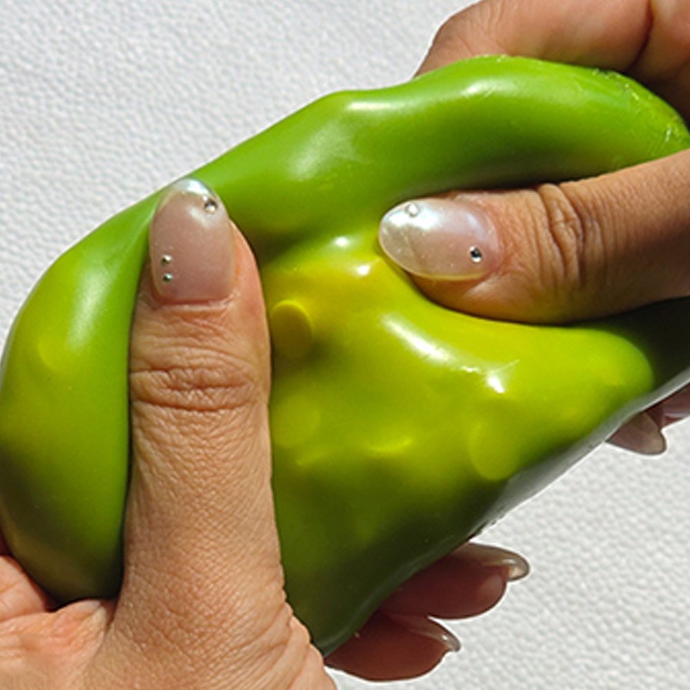 Squeezing open a green Sugar Mango Crunch Slime showing soft white stretchy slime filled with colorful crunch beads and yellow toppings inside, perfect Christmas gift and stress relief sensory toy